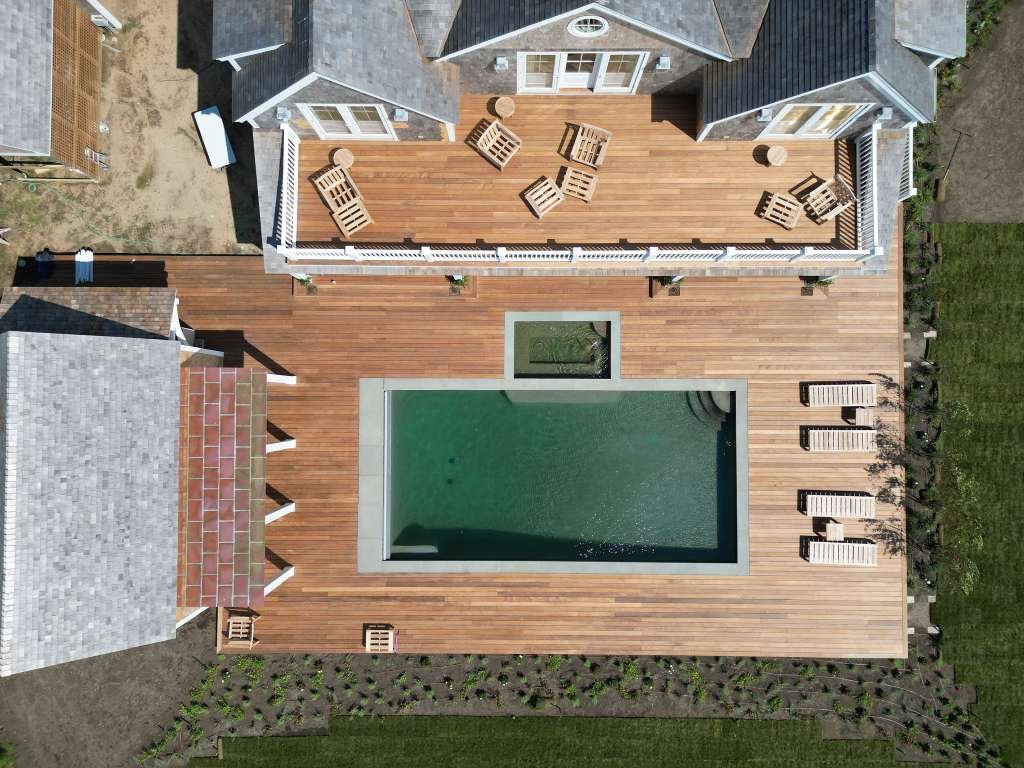 Aerial view of a large hardwood deck beside a backyard pool