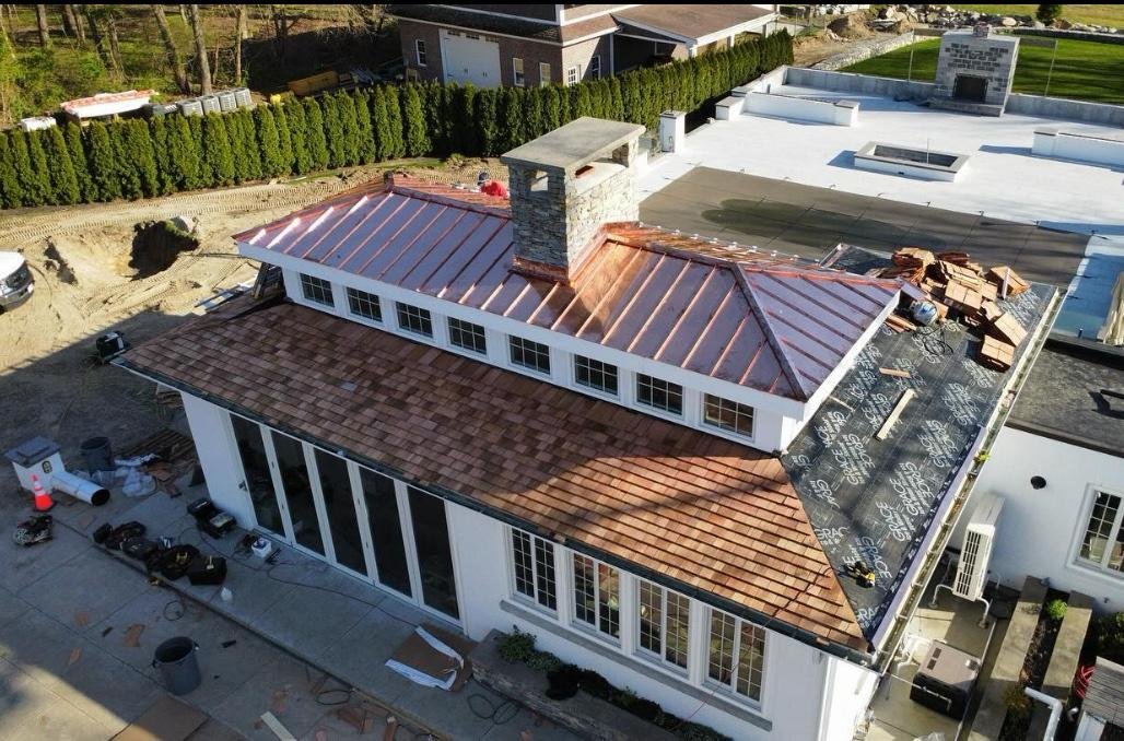 Standing seam metal and cedar shingle roof installation, aerial view